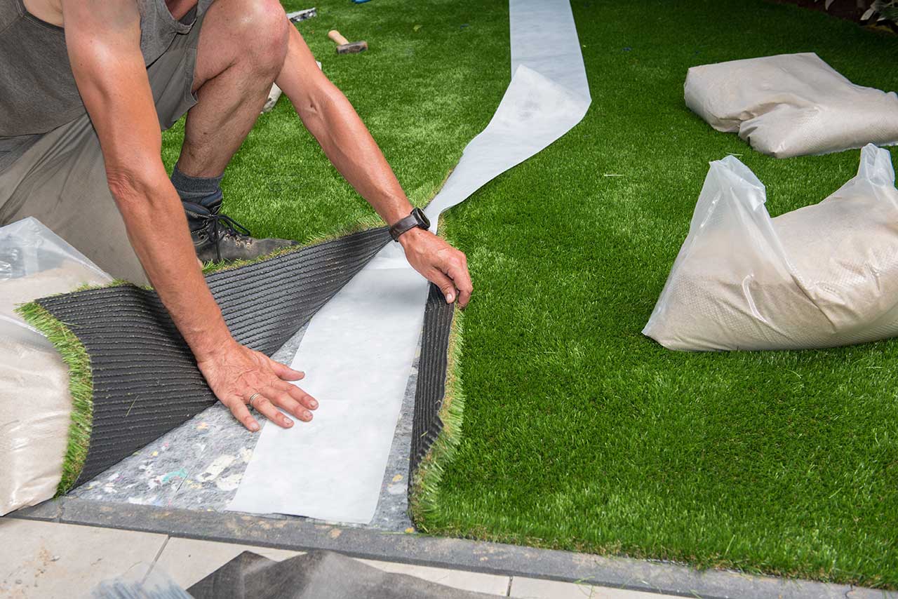 Professional installer cutting and fitting artificial turf